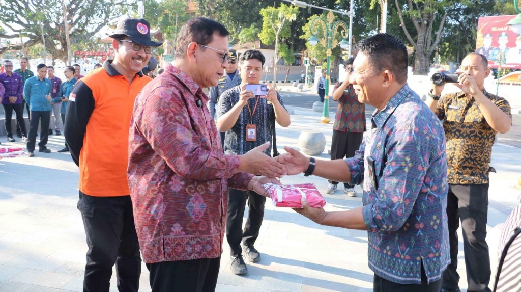 Dokumentasi dari - Bupati Buleleng I Nyoman Sutjidra menyerahkan bendera merah putih kepada masyarakat yang melintasi Titik Nol Kota Singaraja